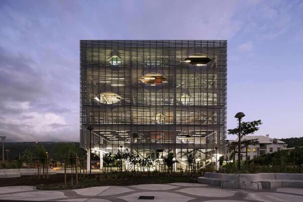 Expanded metal mesh sunshade on a sustainable building, filtering daylight to cut cooling loads and boost comfort